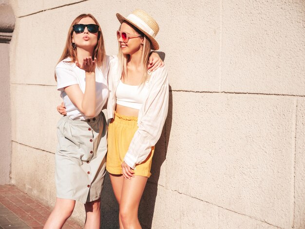 Two young beautiful smiling hipster female in trendy summer clothesSexy carefree women posing in the street in hat Positive pure models having fun at sunset