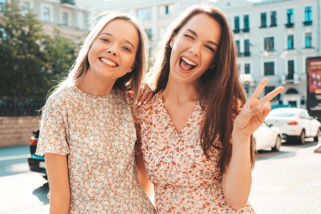 Two young beautiful smiling hipster female in trendy summer clothesSexy carefree women posing in the street Positive pure models having fun at sunset hugging and going crazy Happy and cheerful