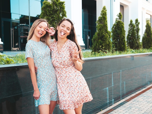 Two young beautiful smiling hipster female in trendy summer dressesSexy carefree women posing in the street Positive pure models having fun at sunset hugging and going crazy