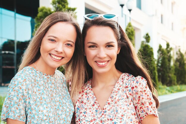 Two young beautiful smiling hipster female in trendy summer dressesSexy carefree women posing in the street Positive pure models having fun at sunset hugging and going crazy