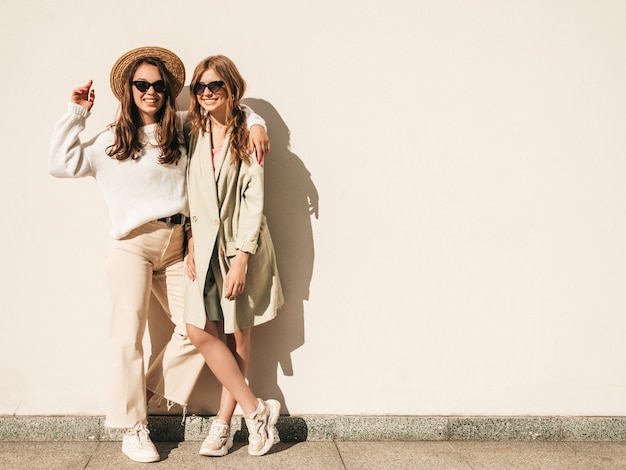 Free photo two young beautiful smiling hipster female in trendy white sweater and coat