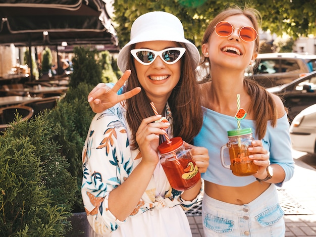 Free photo two young beautiful smiling hipster girls in trendy summer clothes and panama hat