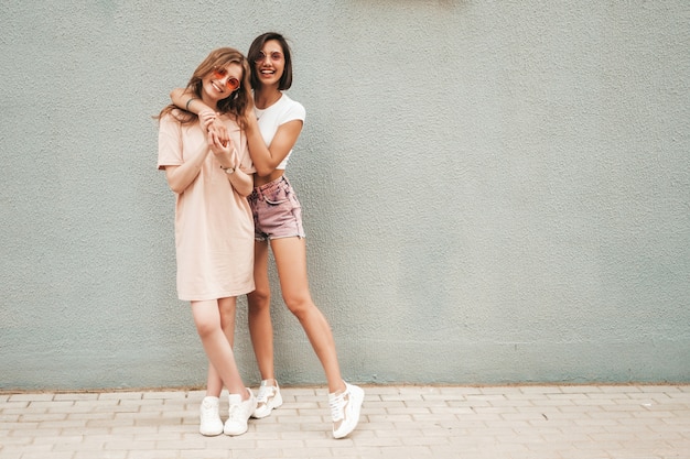 Free photo two young beautiful smiling hipster girls in trendy summer clothes.sexy carefree women posing on street background in sunglasses. positive models having fun and hugging