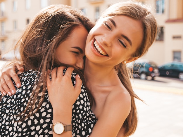 Two young beautiful smiling hipster girls in trendy summer clothes. 