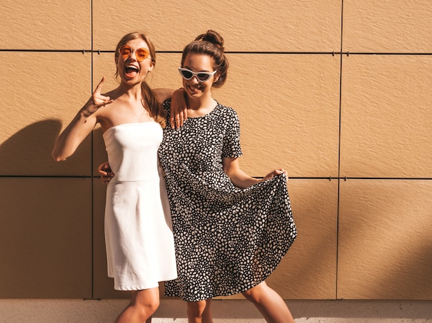 Free photo two young beautiful smiling hipster girls in trendy summer dresses.