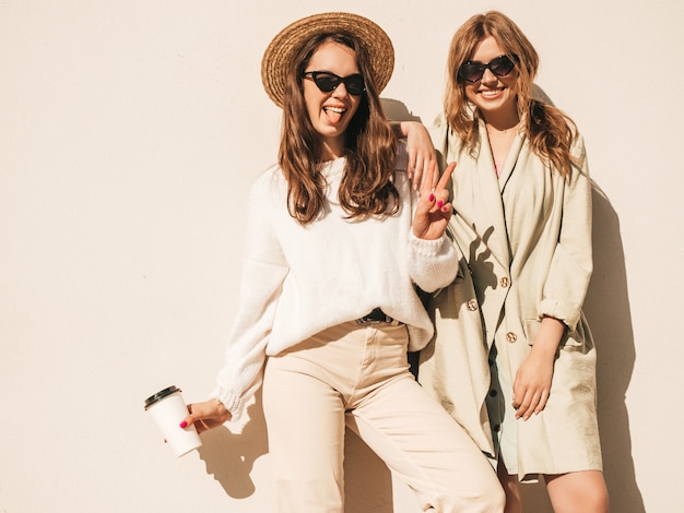 Free photo two young beautiful smiling hipster girls in trendy white sweater and coat