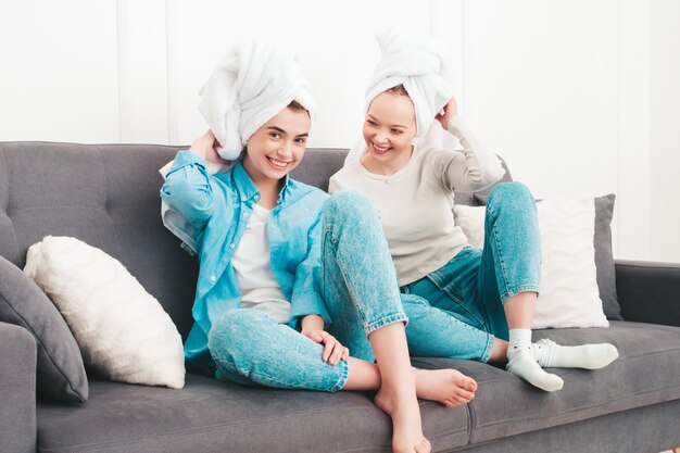 Two young beautiful smiling women sitting at the sofa