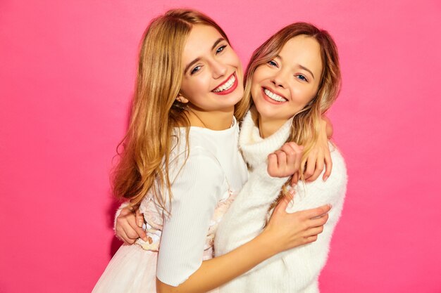 Two young beautiful smiling women in trendy summer white clothes