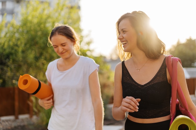 Two young beautiful women in sportswear going to do sports training, gymnastics, yoga