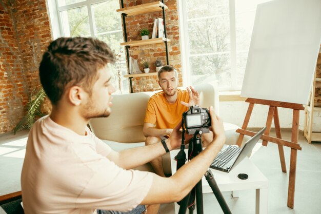 Two young caucasian male bloggers in casual clothes with professional equipment