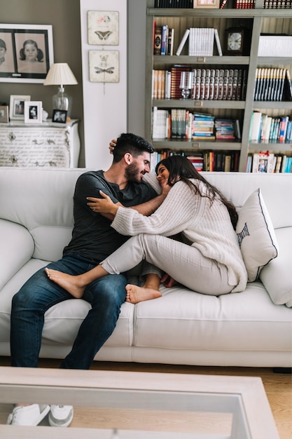 Two young couple sitting on sofa making love in modern house