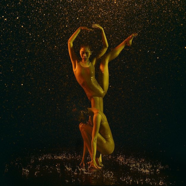 Two young female ballet dancers under water drops