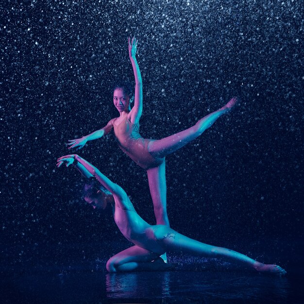 Two young female ballet dancers under water drops