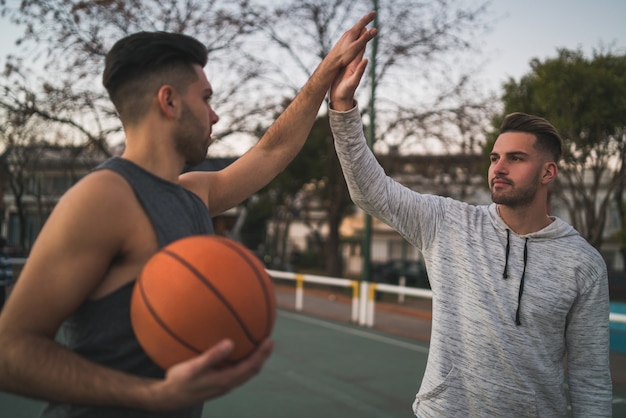 Free photo two young friends playing basketball.