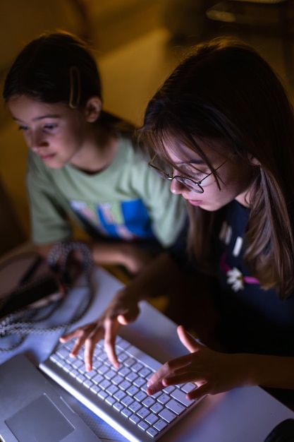 Free photo two young girls at the computer at night