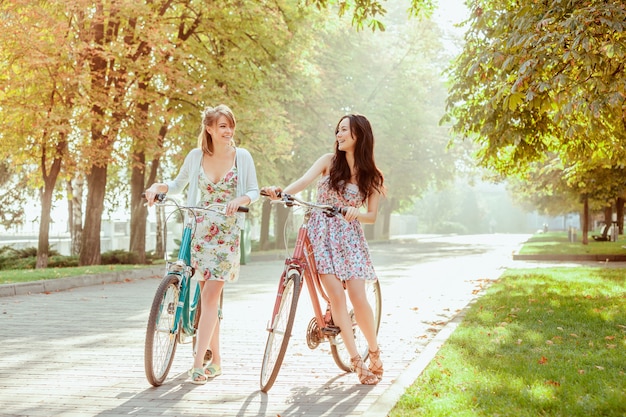 The two young girls with bicycles in park