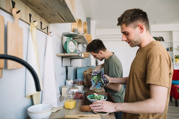 Free photo two young men preparing food in kitchen