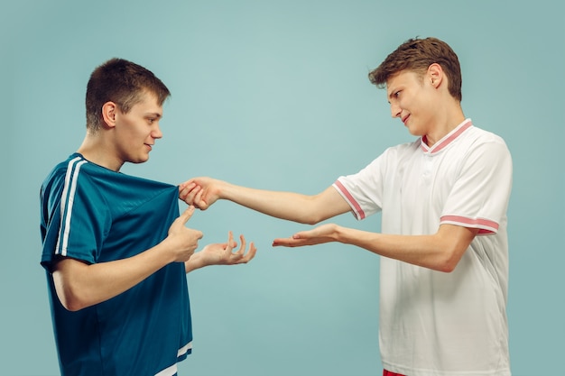 Free photo two young men standing in sportwear isolated. fans of sport, football or soccer club or team. friends' half-length portrait. concept of human emotions, facial expression.