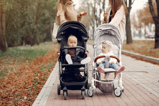 Free photo two young mothers walking in a autumn park with carriages