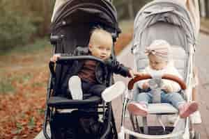 Free photo two young mothers walking in a autumn park with carriages