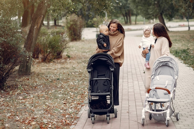 Free photo two young mothers walking in a autumn park with carriages