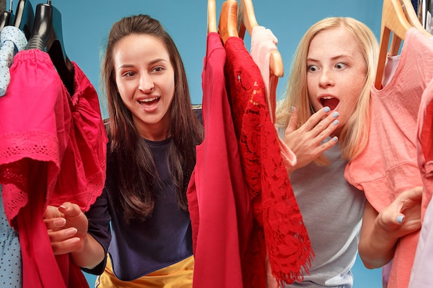 Free photo the two young pretty girls looking at dresses and try on it while choosing at shop