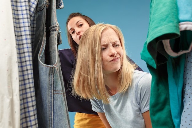 Free photo the two young pretty girls looking at dresses and try on it while choosing at shop