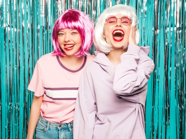 Free photo two young sexy hipster girls in  wigs and red lips.beautiful trendy women in summer clothes having fun