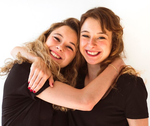 Two young sister embracing each other against white background