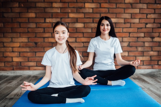 Two young sisters  practicing yoga position in an indoor gym studio. Healthy and wellness lifestyle concept