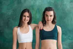 Free photo two young sporty women posing at gym.