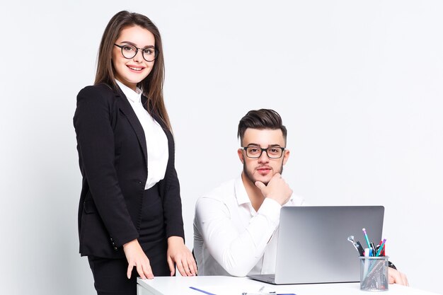 Two young successful people with laptop on white wall