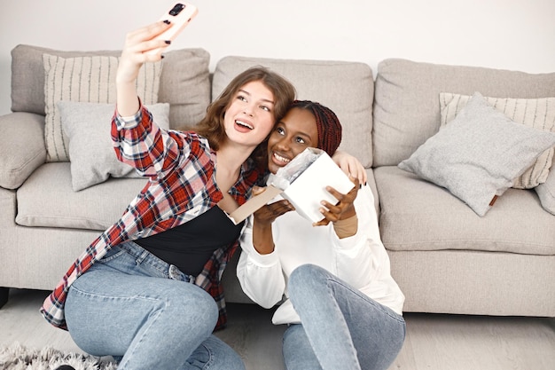 Two young teenage girl sitting on a floor near coach and make a selfie