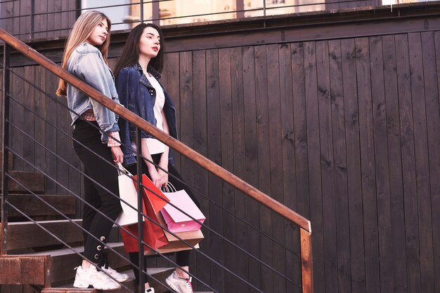 Two young woman carrying shopping bags while walking on the stairs after visiting the stores.