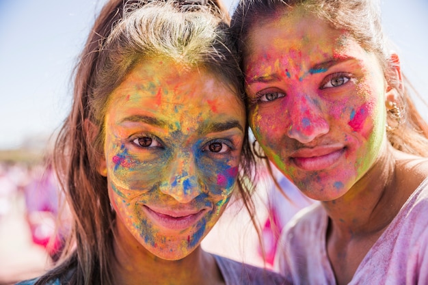 Free photo two young women covered her face with holi color powder