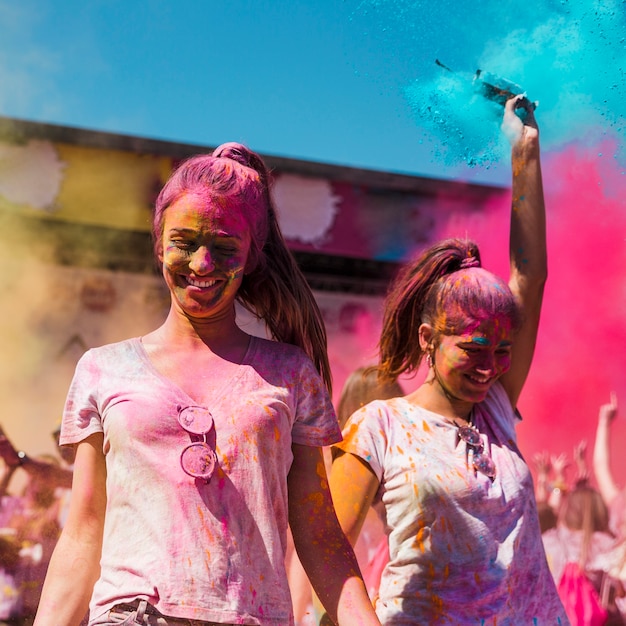 Two young women covered with holi color dancing in the holi festival