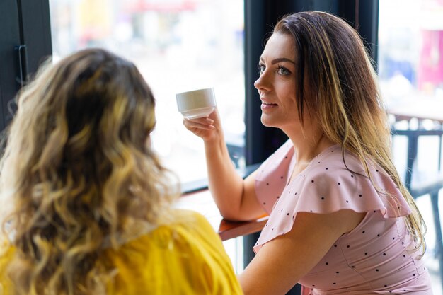 Two young women drinking coffee in cafe