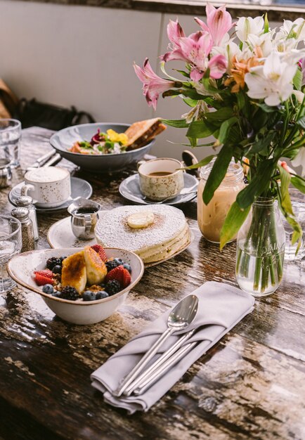 Types of foods, cookies and drinks put on the table in front of the flower vase