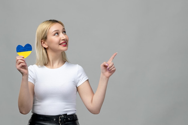 Ukraine russian conflict blonde cute girl holding ukrainian heart looking up