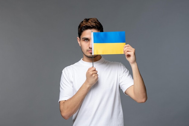 Ukraine russian conflict courageous handsome guy in white shirt with covering face with flag