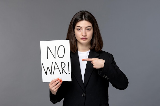 Free photo ukraine russian conflict cute young dark hair woman in black blazer holding no war sign