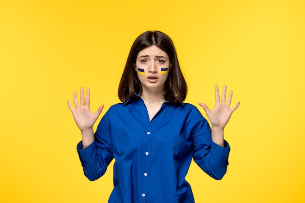 Ukraine russian conflict young pretty girl flags on cheeks yellow background saying to stop