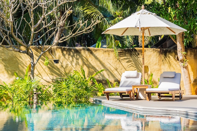 Umbrella and chair around outdoor swimming pool in resort hotel for vacation leisure