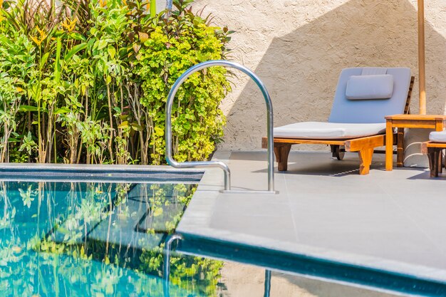 Umbrella and chair around swimming pool neary sea ocean beach with blue sky and white cloud