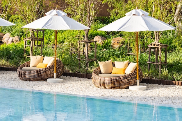 Free photo umbrella and deck chair around outdoor swimming pool in hotel resort with sea ocean beach and coconut palm tree