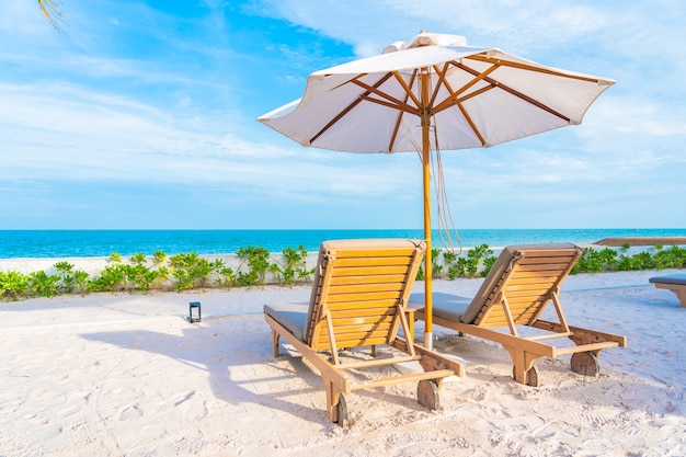 Umbrella and deck chair around outdoor swimming pool in hotel resort with sea ocean beach and coconut palm tree