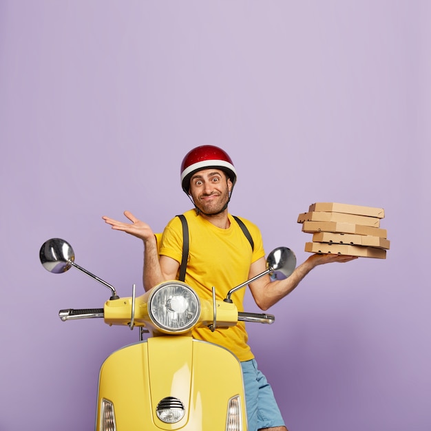 Free photo unaware deliveryman driving yellow scooter while holding pizza boxes