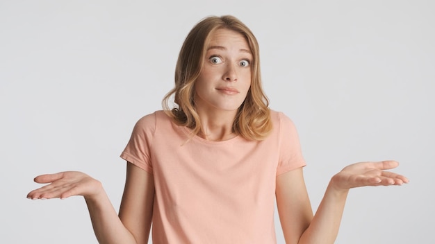 Free photo uncertain blond girl shrugging shoulders showing i dont know gesture on camera isolated on white background body language concept