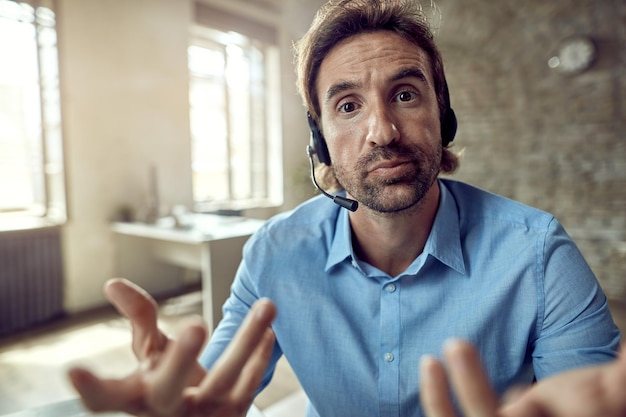 Free photo uncertain businessman gesturing while working in the office and looking at the camera