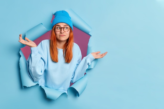 Uncertain puzzled redhead woman spreads palms and.